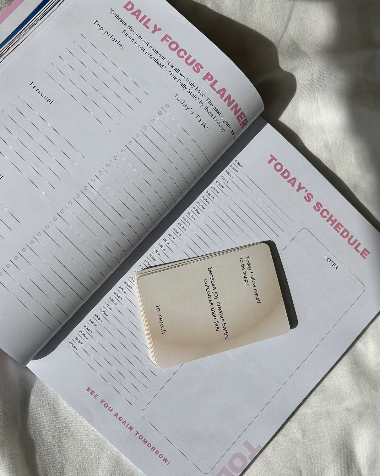 The in·reach daily focus planner open beside an affirmation card deck
