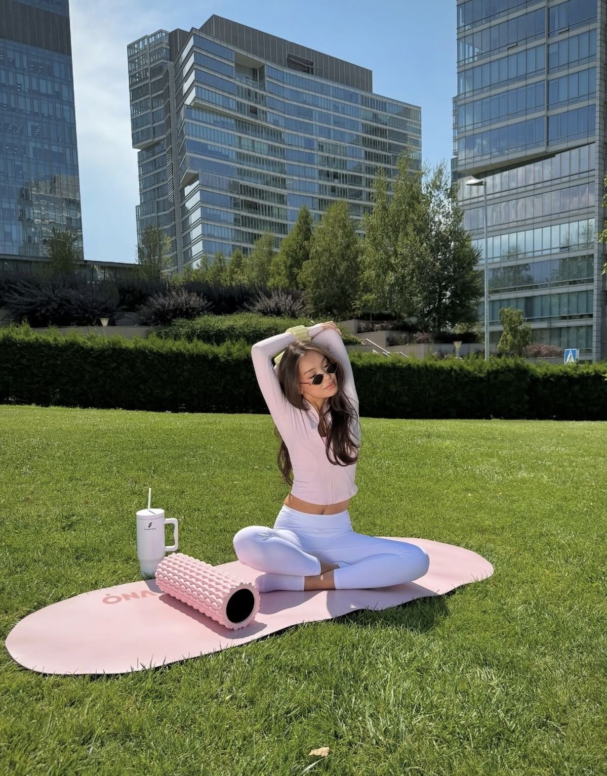 Woman stretching on a pink mat in a sunny city park